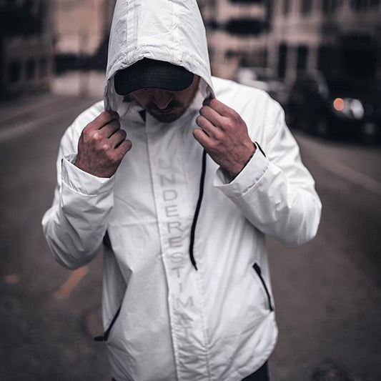 man puts hoody of all-weather tech jacket over his head