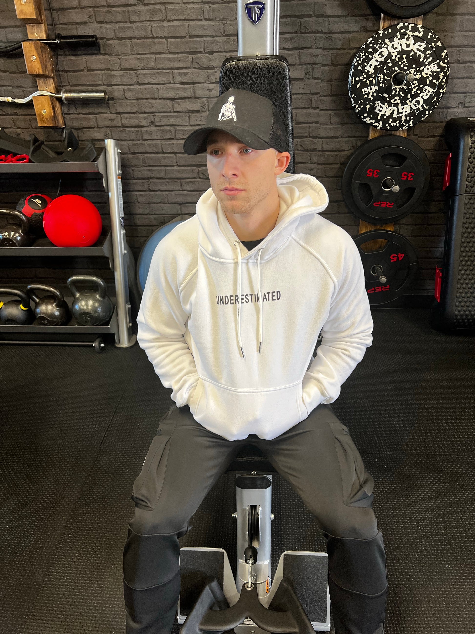 Guy sitting on lat pull down machine in black warrior joggers.  