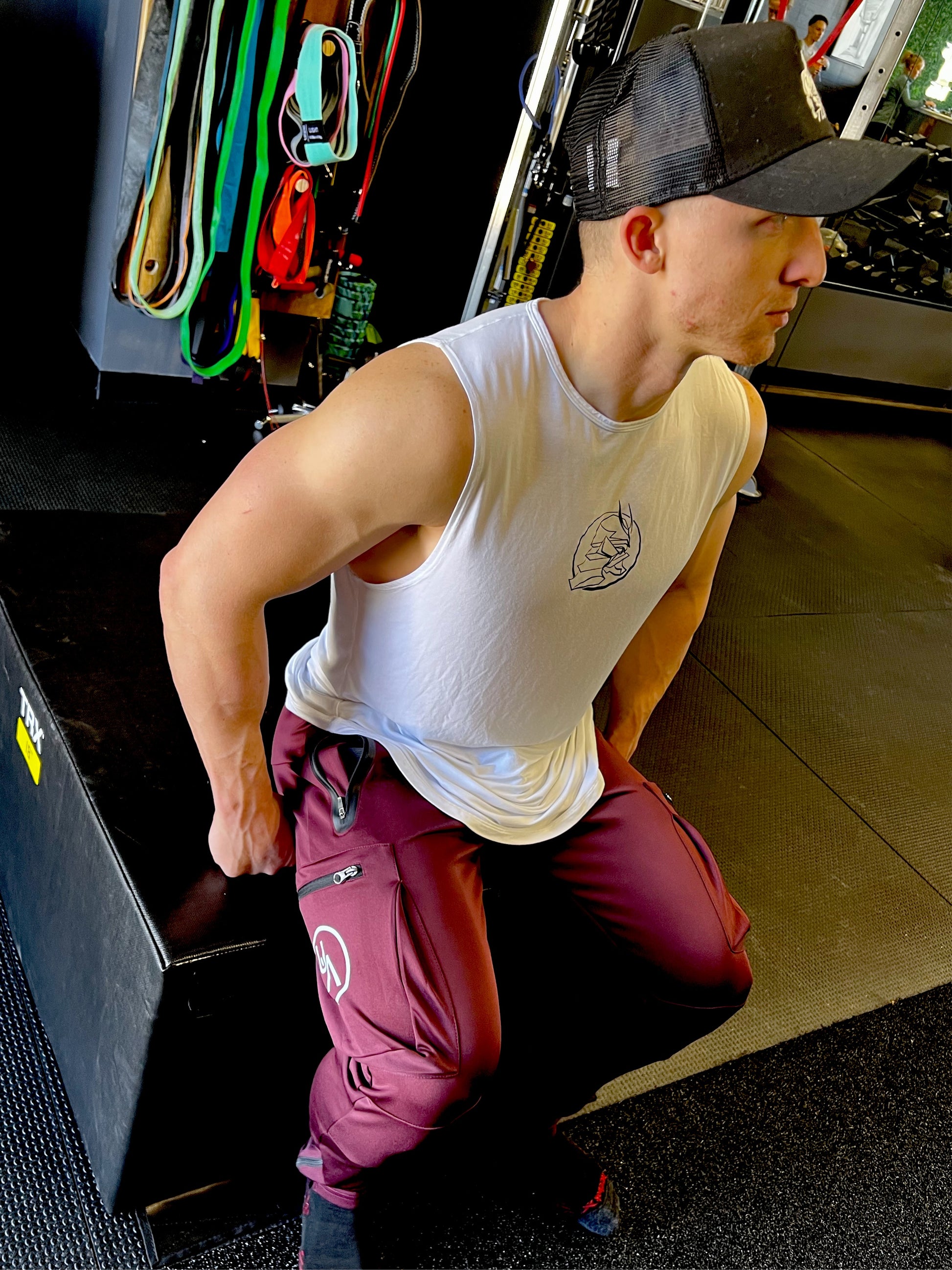 Man Sitting in gym in Maroon Warrior joggers.  Zipper side pockets and logo showing.